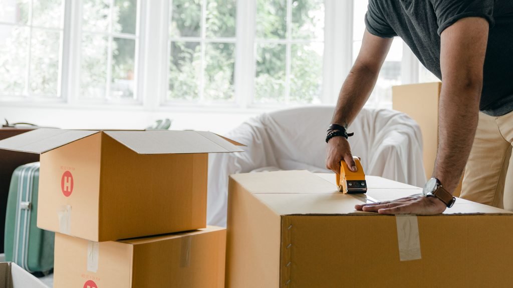 Person sealing moving boxes while preparing for a move