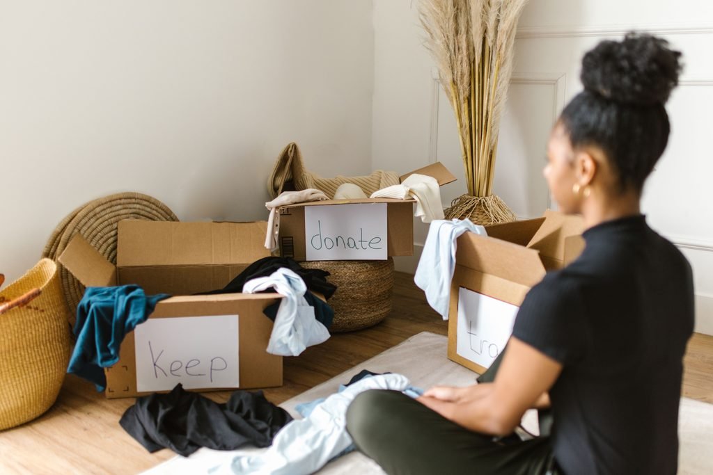Woman sorting household items into keep and donate boxes.