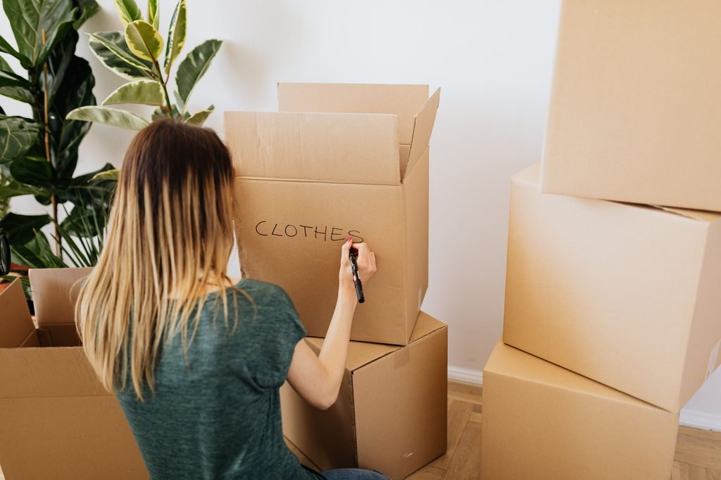 Woman labeling a box of clothes while packing for a move.